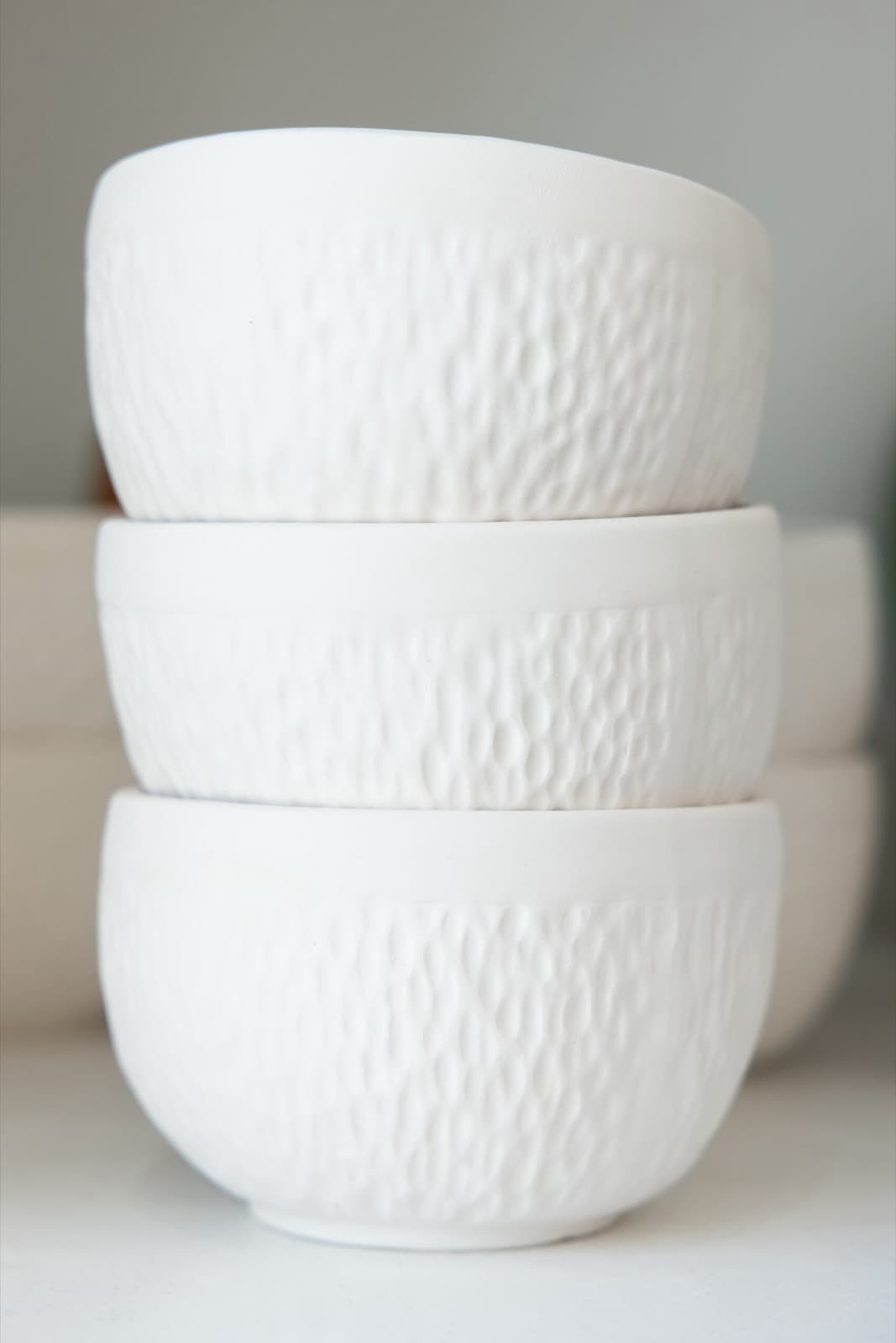 Bisque pottery lined up on studio shelves